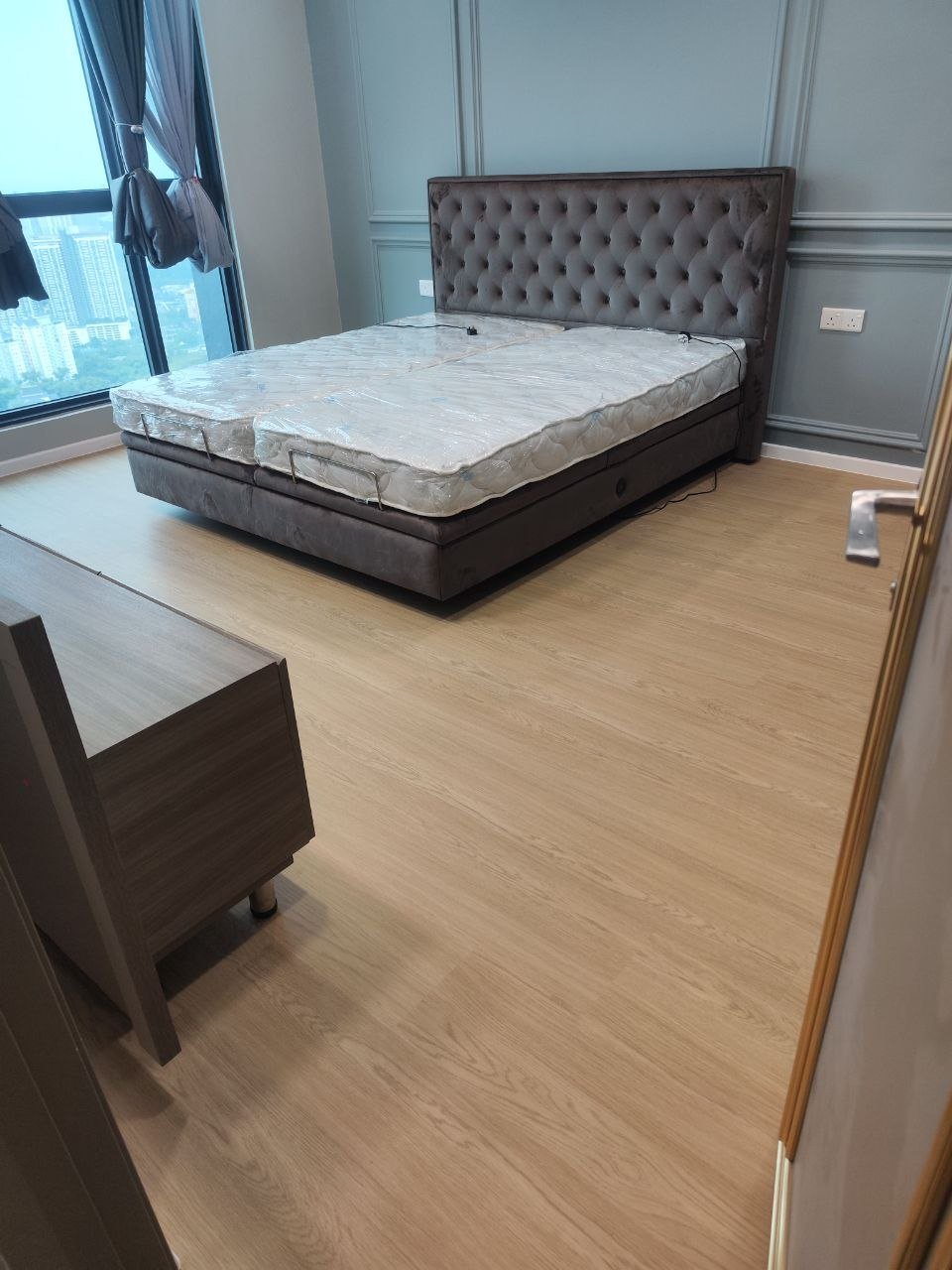 Master bedroom with grey tufted bed and blue-grey panelled walls over new oak-look SPC flooring in Bloomsvale KL
