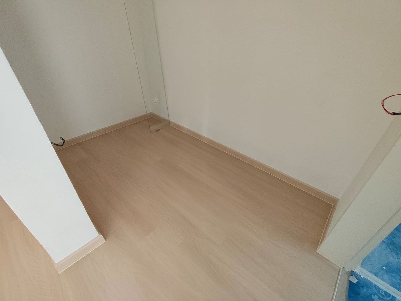 Neat junction of light oak-look SPC flooring and matching skirting at a doorway in a D'Clover Residences condo