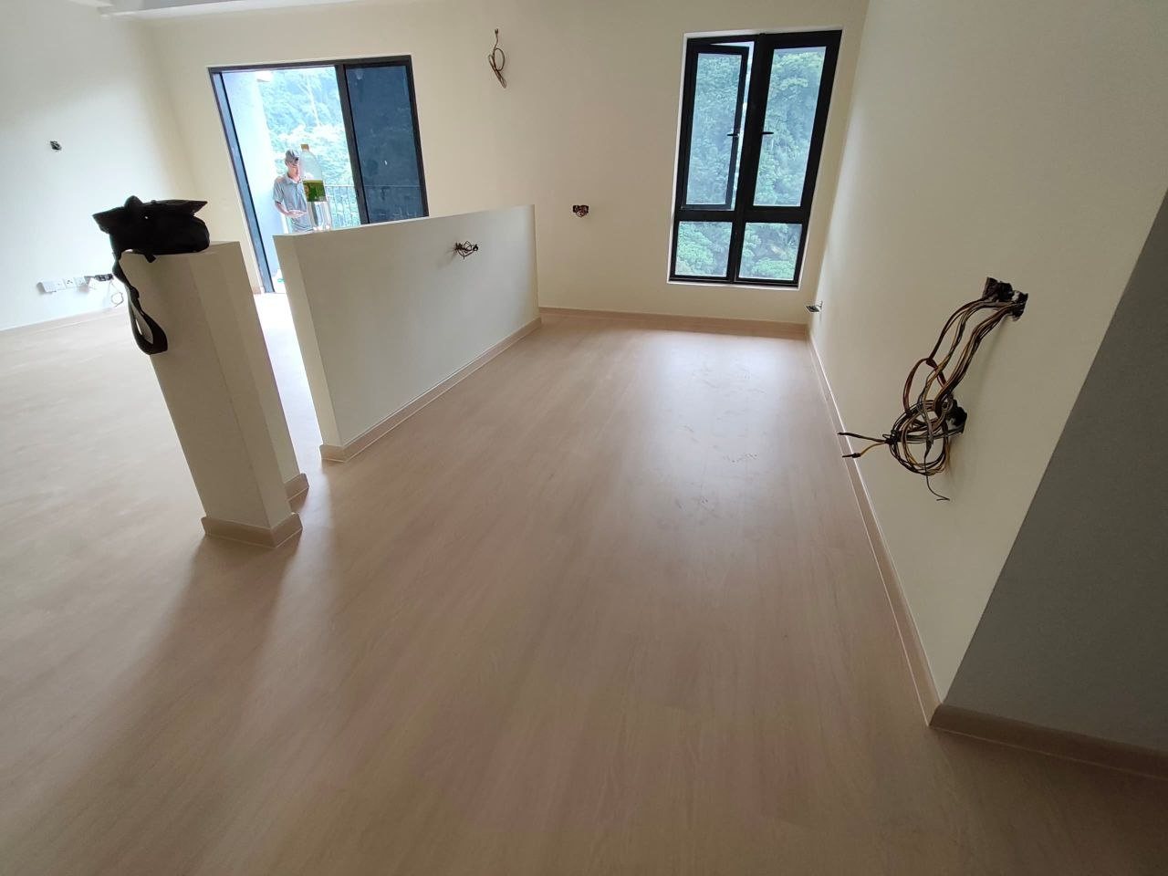Space with a half wall, windows overlooking forest greenery and light oak-look SPC flooring in a D'Clover Residences unit