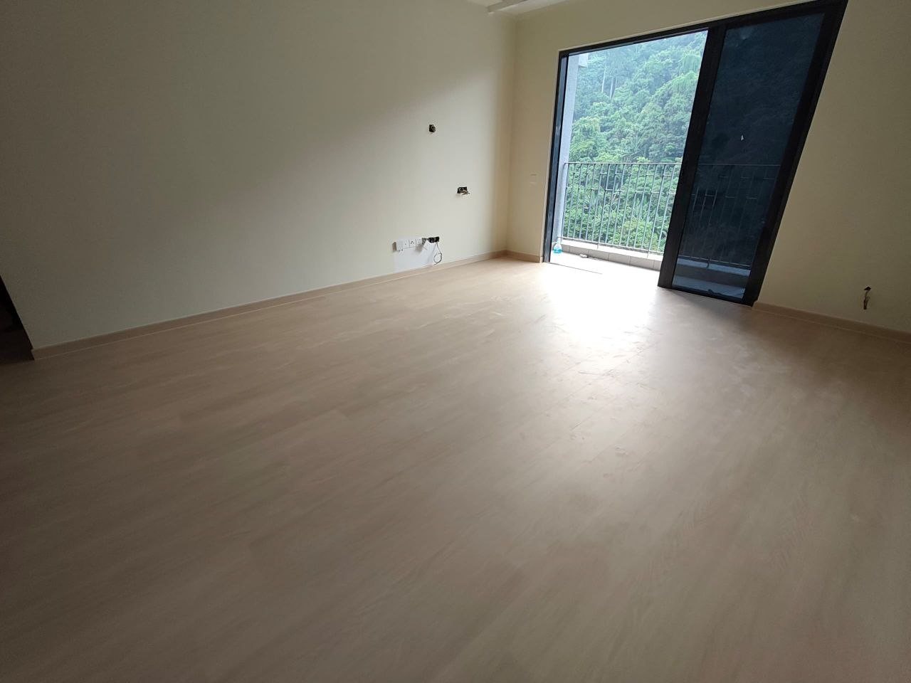 Room with light oak-look SPC flooring and a balcony door overlooking forest greenery at D'Clover Residences, Damansara Perdana
